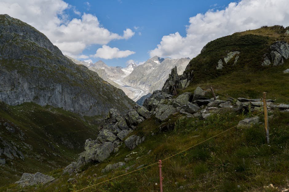 A stunning landscape of the Fiesch Glacier surrounded by rugged Swiss Alps under a bright blue sky.