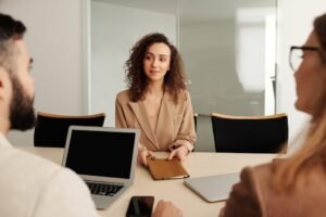 A woman in a business suit participates in a job interview, showcasing professionalism and modern office environment.