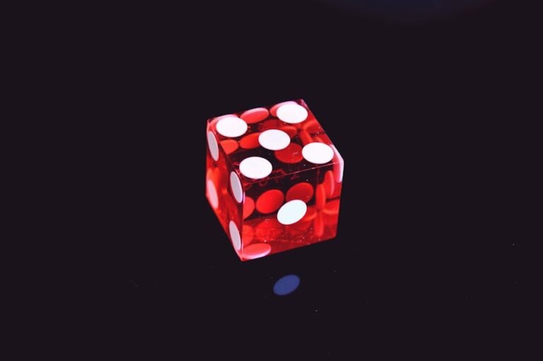 Close-up of a red transparent dice on a black background with vivid white dots creating a high contrast visual.