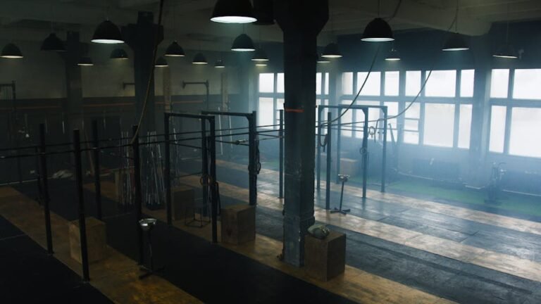 Spacious industrial-style gym interior with no people, showcasing equipment and natural light.