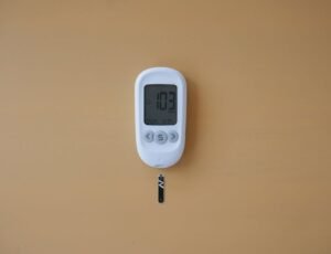 Close-up of a digital glucose meter displaying blood sugar level on a brown surface.