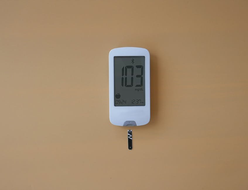 A close-up of a digital blood glucose meter displaying 103 mg/dL on a simple background.