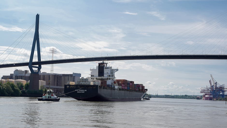 Container ship navigates beneath Köhlbrand Bridge in Hamburg, showcasing global trade in action.
