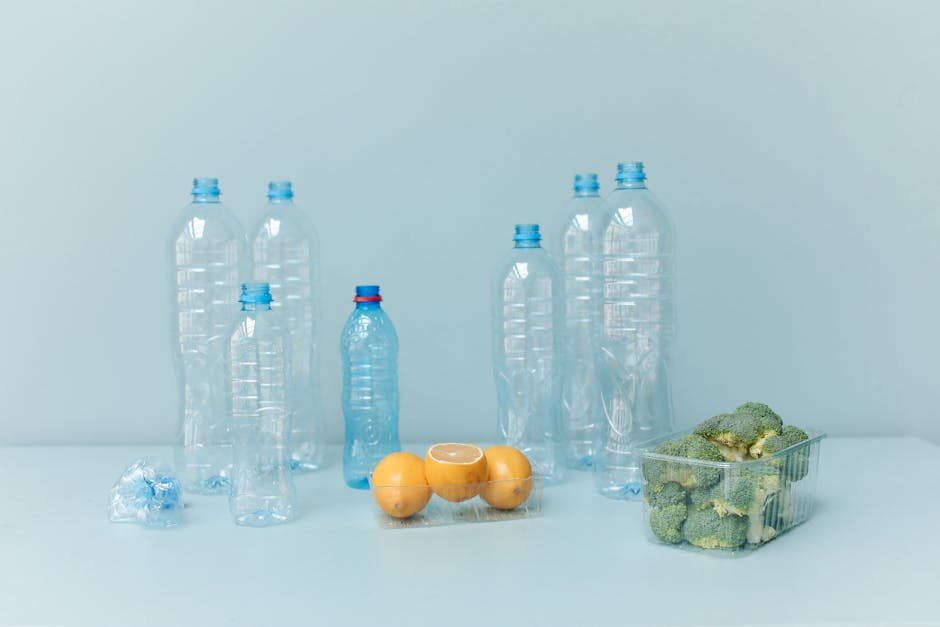 Stock photo of plastic bottles, lemons, and broccoli on a light blue background symbolizing waste.