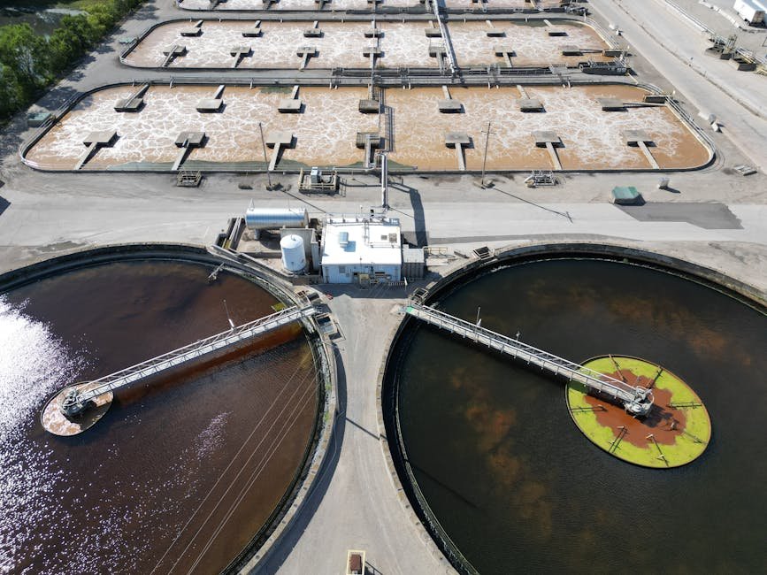 Aerial shot of an industrial water treatment plant with large circular tanks.